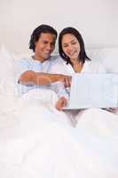 Couple sitting on the bed with their notebook