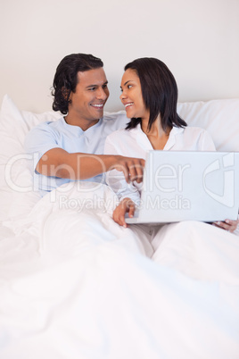 Couple sitting on the bed surfing the internet