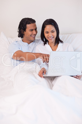 Couple sitting on the bed surfing the web