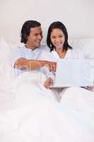 Couple sitting on the bed surfing the web