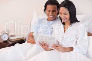 Couple sitting on the bed using tablet pc