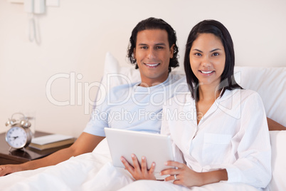 Couple sitting on the bed with their tablet pc
