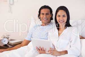 Couple sitting on the bed with their tablet pc