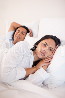 Displeased woman lying next to snoring boyfriend