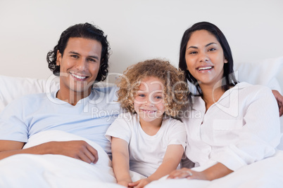 Happy family sitting on the bed together Happy family sitting on the bed together