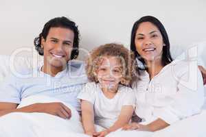 Happy family sitting on the bed together