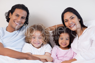 Smiling family sitting on the bed together