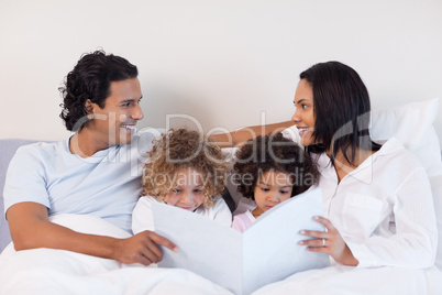 Family reading a story in the bedroom