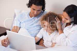 Family with laptop sitting on the bed