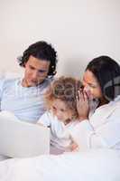 Family sitting on the bed with laptop