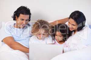 Family sitting on the bed surfing the internet