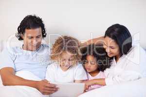 Family sitting on the bed surfing the web