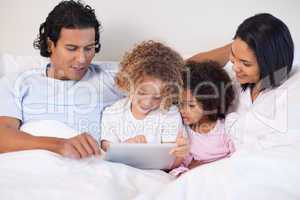 Family sitting on the bed using tablet
