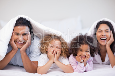 Joyful family hiding under the blanket