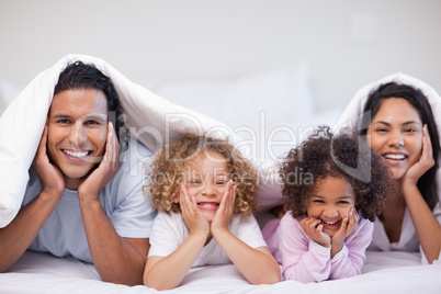 Happy family hiding under the blanket