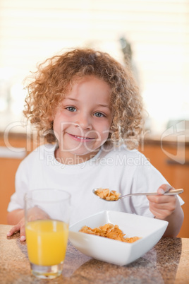 Happy girl eating cereals for breakfast