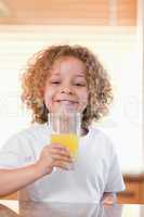 Smiling girl having orange juice in the kitchen
