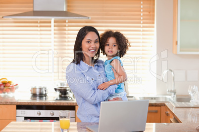 Mother and daughter with notebook in the kitchen together