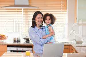 Mother and daughter with notebook in the kitchen together