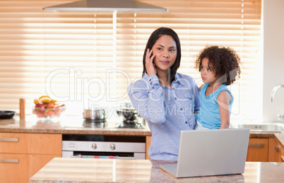 Mother and daughter with cellphone and laptop in the kitchen tog