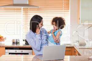 Mother and daughter with cellphone and notebook in the kitchen t