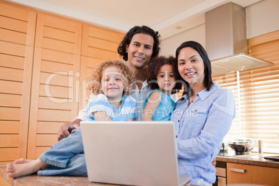 Happy family with laptop standing in the kitchen together