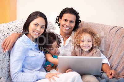 Family using laptop on the sofa together