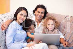 Family using laptop on the sofa together
