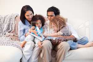 Family on the sofa looking at photo album together