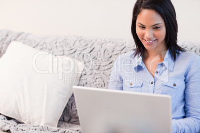 Smiling woman on the couch surfing the internet