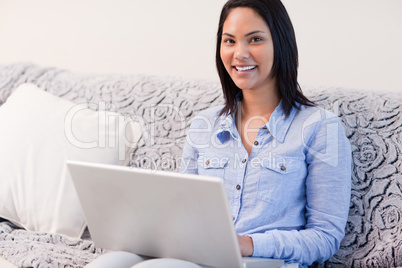 Smiling woman on the sofa with her laptop