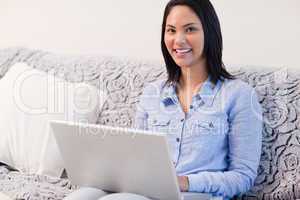 Smiling woman on the sofa with her laptop