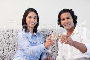 Couple celebrating with sparkling wine on the sofa