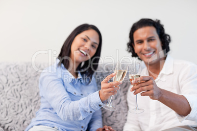 Couple celebrating with sparkling wine on the couch