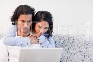 Woman hugging her boyfriend that is working on his notebook