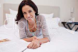 Woman with magazine laying on the bed