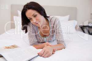 Woman laying on the bed reading a magazine