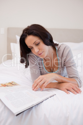 Woman laying in the bedroom reading a magazine