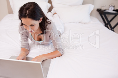 Woman lying on the bed using her laptop