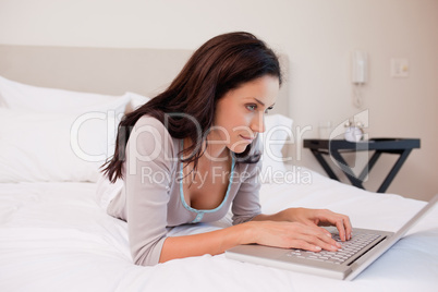 Woman lying on the bed surfing the internet
