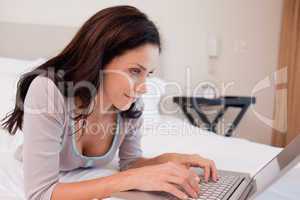 Woman lying on the bed using her notebook