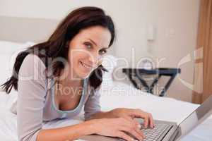 Smiling woman with her laptop on the bed