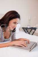 Woman working on the laptop in the bedroom