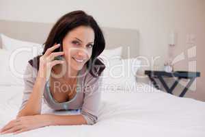 Smiling woman on the bed having a phone call