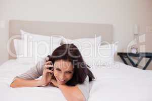Woman having a joyful phone call on her bed