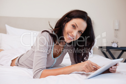 Smiling woman with tablet on the bed