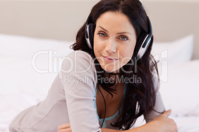 Smiling woman enjoying music on her bed