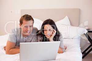Couple using laptop on the bed together