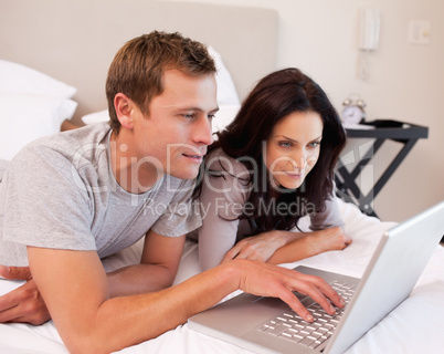 Couple using notebook together in the bedroom