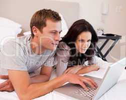 Couple using notebook together in the bedroom